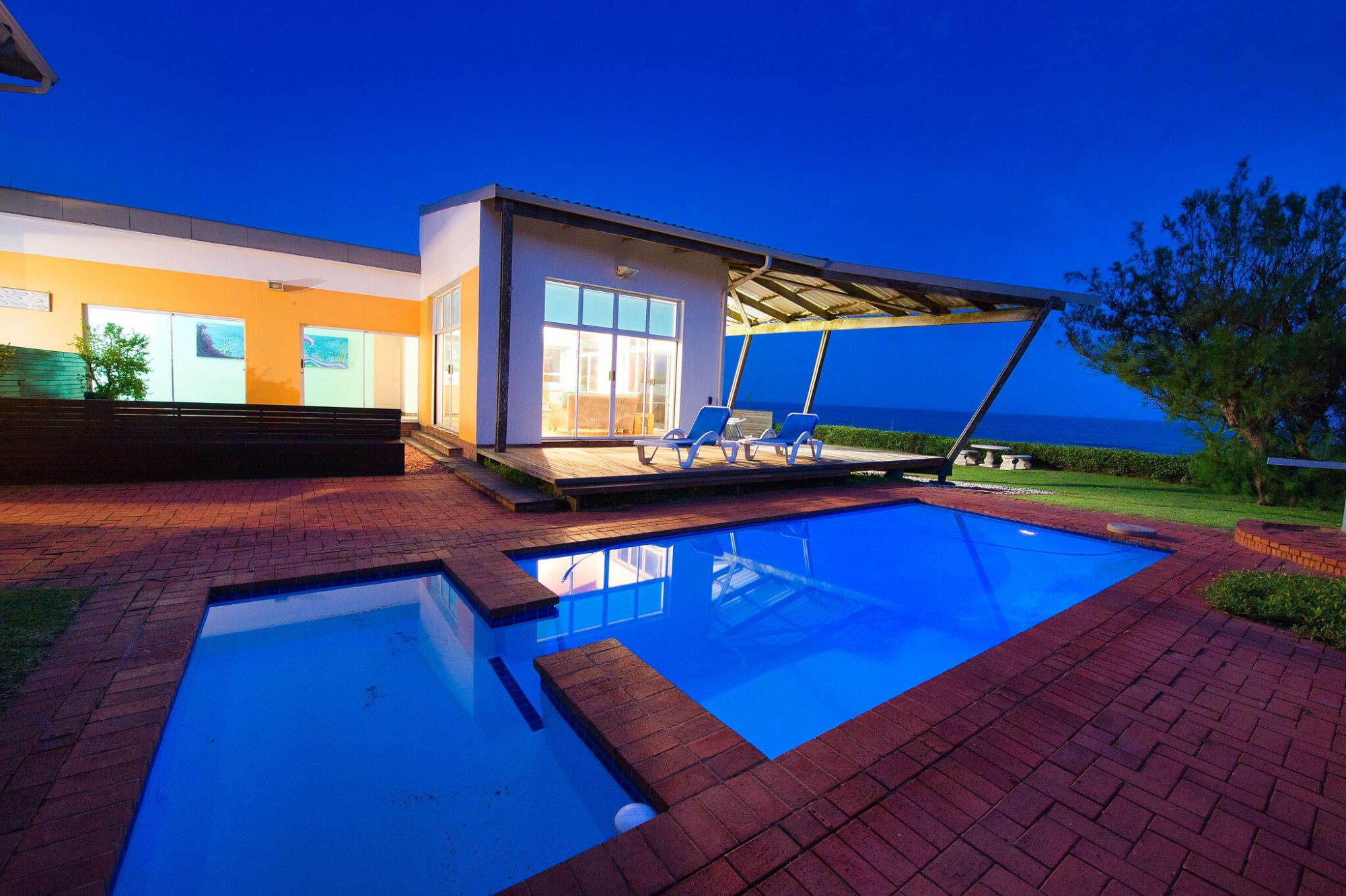 Pool view from outside during night time, looking towards the holiday home and the ocean